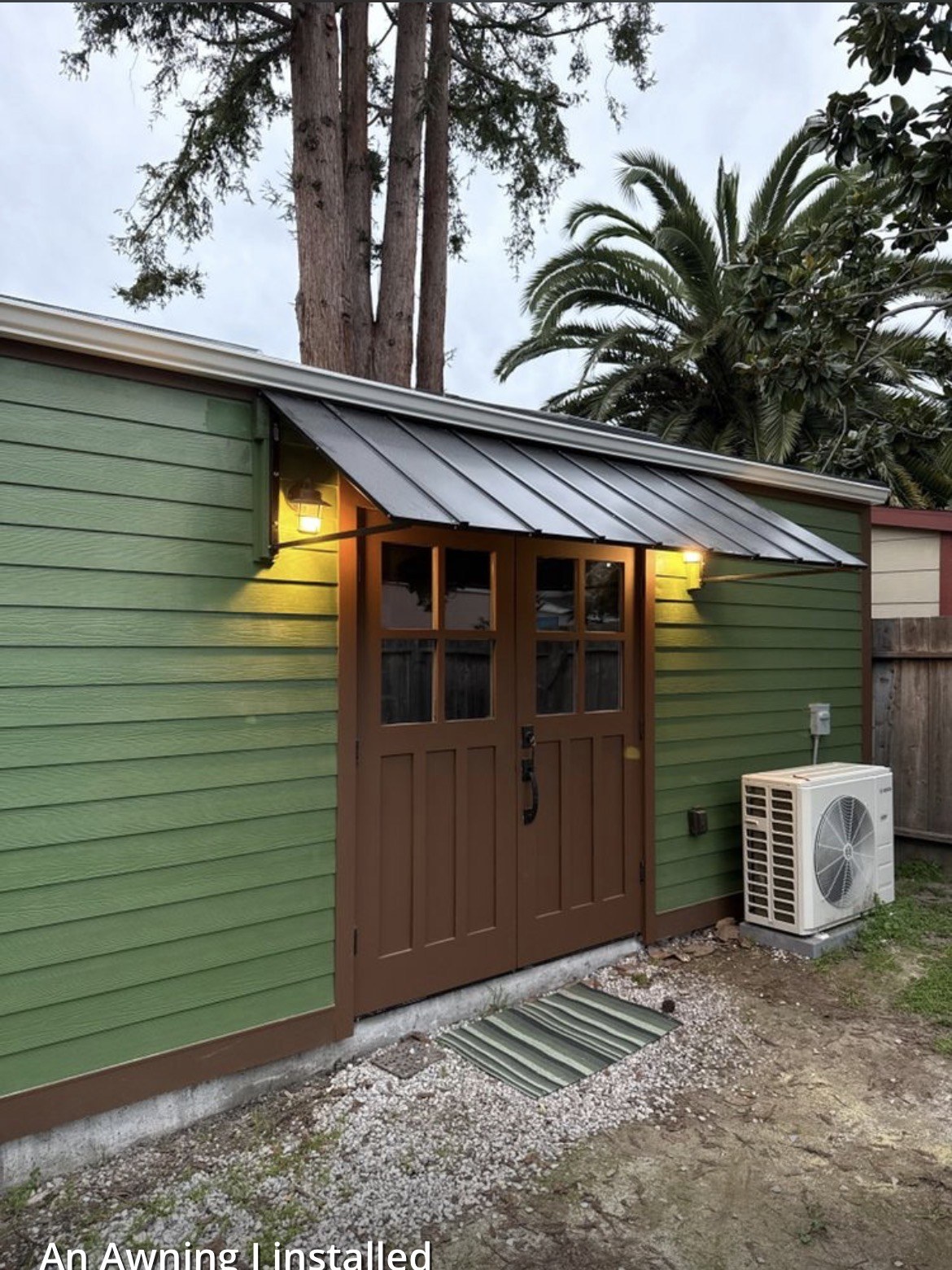 Metal awning installed over craftsman doors on a green home